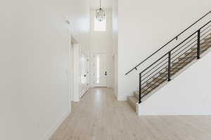 Entrance foyer with a high ceiling, light wood-style floors, and suspended lighting