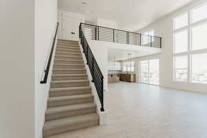 Stairs featuring a high ceiling, wood finished floors, and recessed lighting