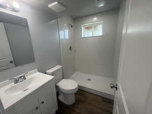 Bathroom with vanity, a shower stall, dark wood finished floors, and a textured ceiling