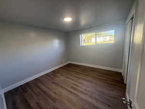 Unfurnished bedroom featuring a closet and dark wood-style flooring