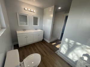 Bathroom with double vanity, dark wood-style floors, a tile shower, and recessed lighting