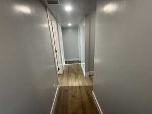 Corridor with light wood-style flooring and recessed lighting