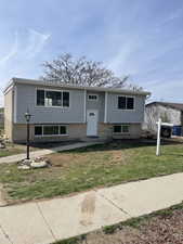 Split foyer home featuring brick siding and a front yard