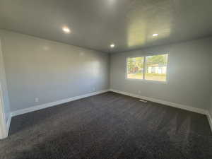 Spare room with dark colored carpet, a textured ceiling, and recessed lighting
