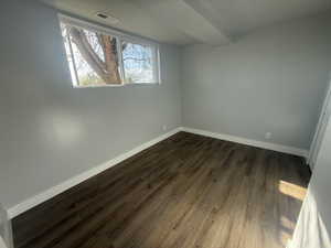 Empty room featuring dark wood-style floors and baseboards