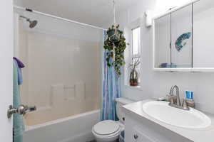 Bathroom featuring vanity, a textured ceiling, and shower / bath combination with curtain