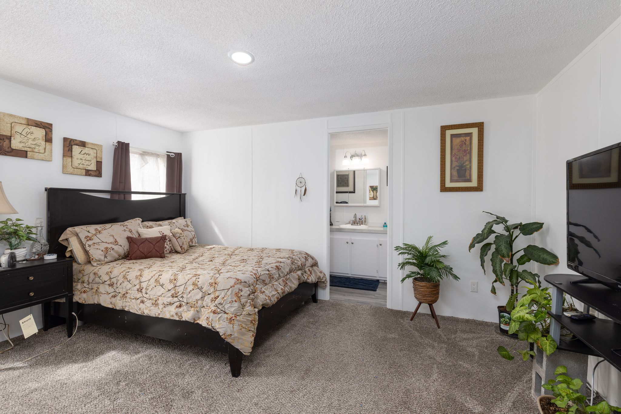 Carpeted bedroom featuring a textured ceiling and ensuite bathroom