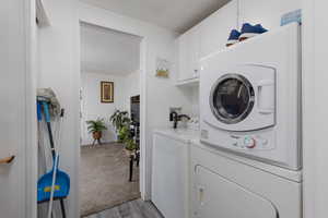 Laundry room featuring a textured ceiling, cabinet space, light wood-type flooring, and washer and clothes dryer