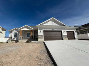 Craftsman inspired home with board and batten siding, a garage, stone siding, and concrete driveway