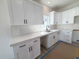 Kitchen featuring white cabinetry, light stone counters, wood finished floors, and tasteful backsplash