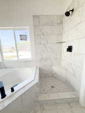 Bathroom featuring a bath and a marble finish shower