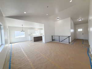 Unfurnished living room with healthy amount of natural light, vaulted ceiling, and recessed lighting