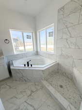 Bathroom featuring a garden tub, marble finish floors, a marble finish shower, and plenty of natural light