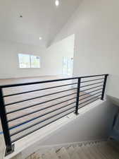 Stairway with recessed lighting, a high ceiling, and wood finished floors