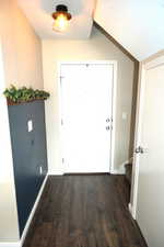 Entrance foyer featuring dark wood-type flooring and lofted ceiling