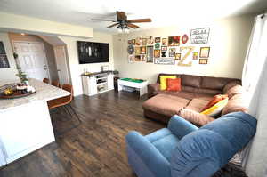 Living room featuring dark wood-style floors and a ceiling fan