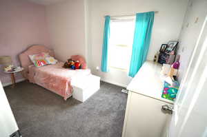 Bedroom featuring dark colored carpet and baseboards