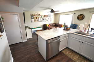 Kitchen with a kitchen breakfast bar, light countertops, dishwasher, dark wood-style floors, and open floor plan