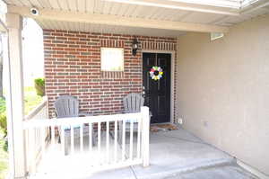 Entrance to property with a porch, brick siding, and stucco siding