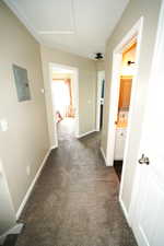 Corridor featuring dark colored carpet and electric panel