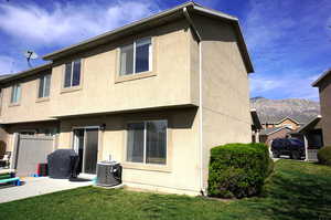 Back of house with a lawn, stucco siding, a mountain view, and a patio area