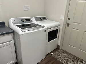 Laundry room with washer and dryer, dark wood-style floors, and cabinet space