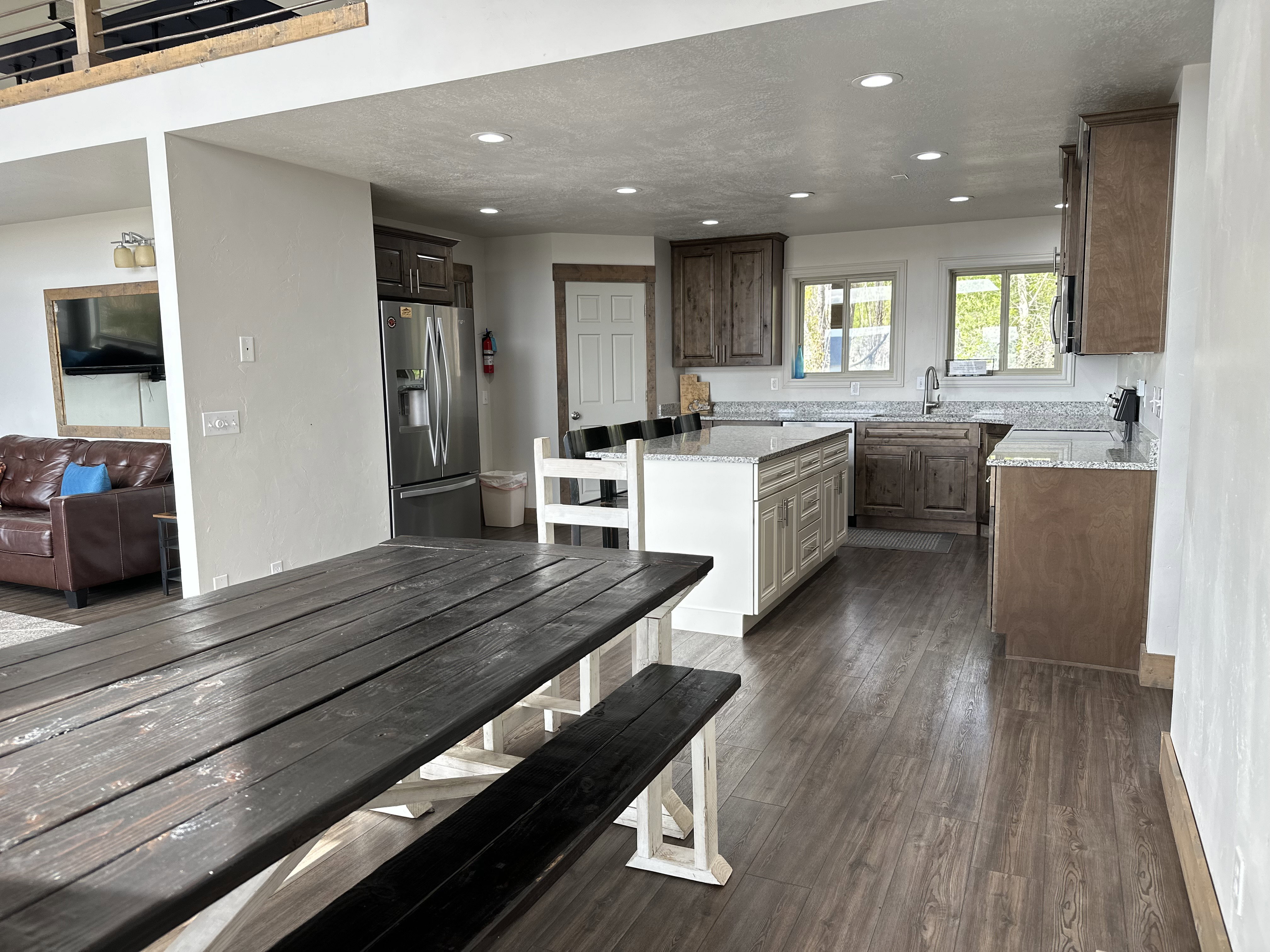 Two tone kitchen with light stone countertops, stainless steel appliances, dark wood-style floors, recessed lighting, and a kitchen island