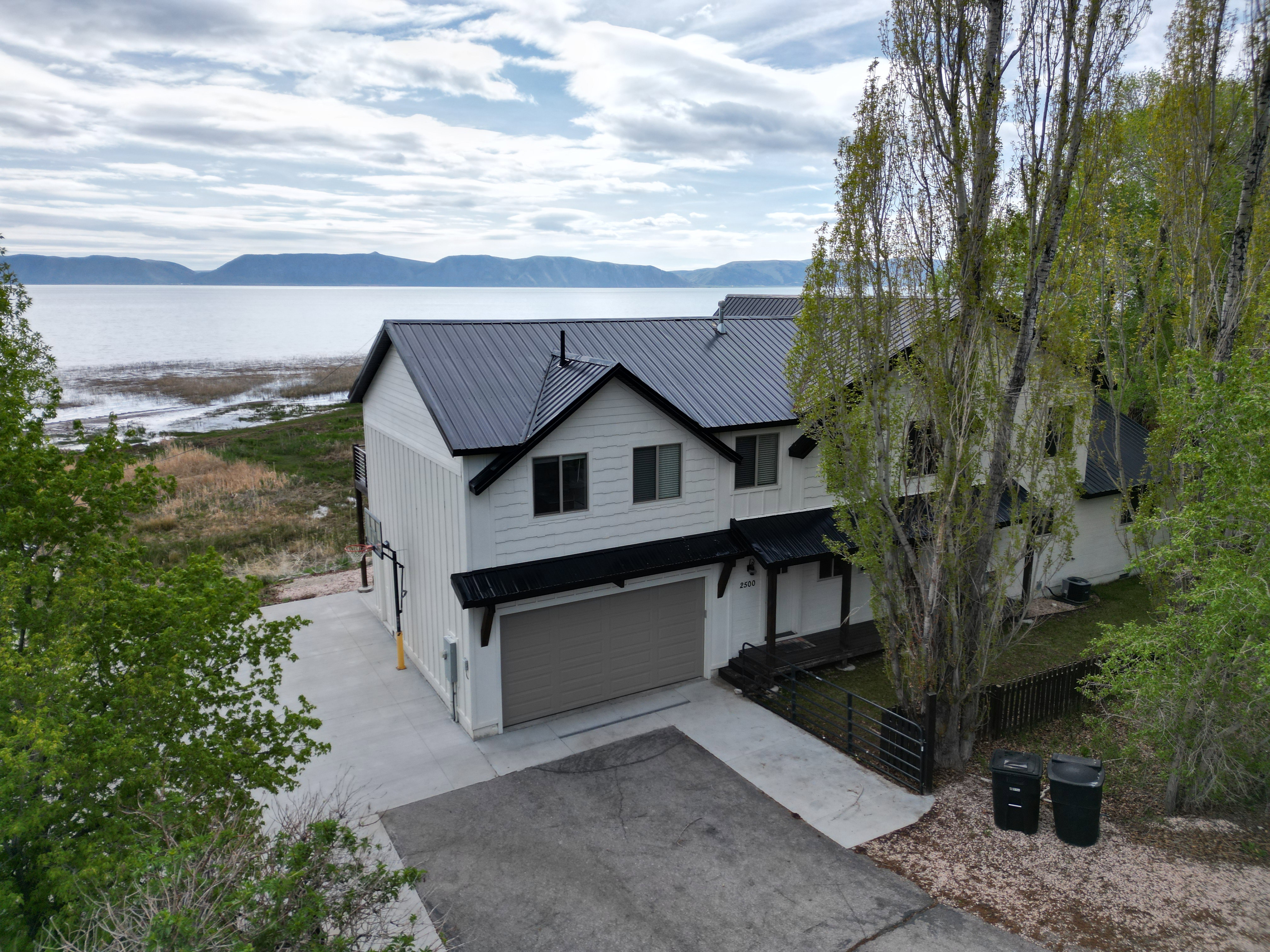 Modern farmhouse style home with a garage, a metal roof, driveway, and a water and mountain view