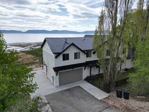 Modern farmhouse style home with a garage, a metal roof, driveway, and a water and mountain view