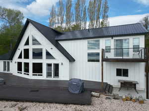 Back of house with board and batten siding, a wooden deck, and a metal roof