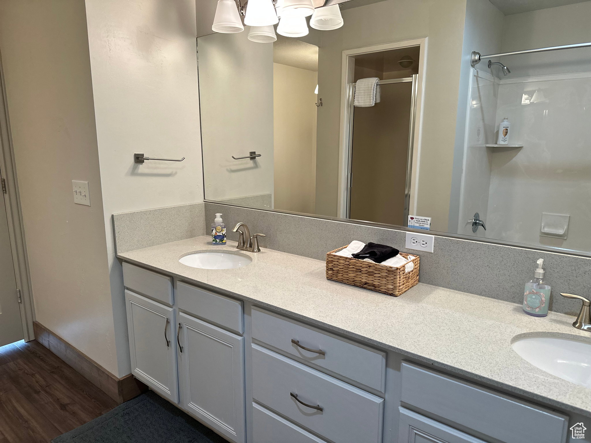 Bathroom with a shower stall, double vanity, and dark wood-style floors