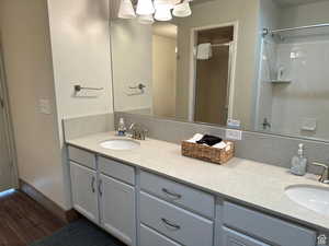 Bathroom with a shower stall, double vanity, and dark wood-style floors