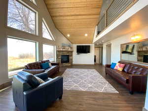 Living room with a stone fireplace, a vaulted wood ceiling, recessed lighting, and dark wood-style flooring