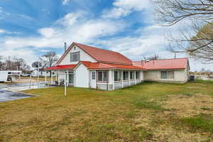 Back of property featuring a lawn and a metal roof