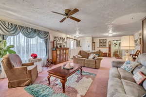 Carpeted living area featuring a textured ceiling and a ceiling fan