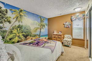 Bedroom featuring carpet, a textured ceiling, and an accent wall