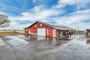 View of outdoor structure featuring solar panels and asphalt driveway