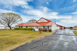 View of front facade with a metal roof, a front lawn, and driveway