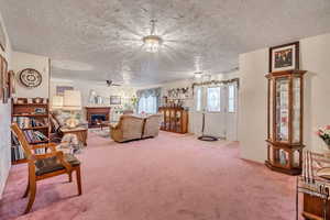 Living area with a textured ceili, light colored carpet, and ceiling fan
