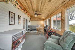 Sunroom / solarium with a jacuzzi, a vaulted wooden ceiling, ceiling fan, wooden walls, and carpet floors