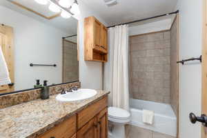 Bathroom with vanity, shower / bath combination with curtain, light tile patterned flooring, and a textured ceiling