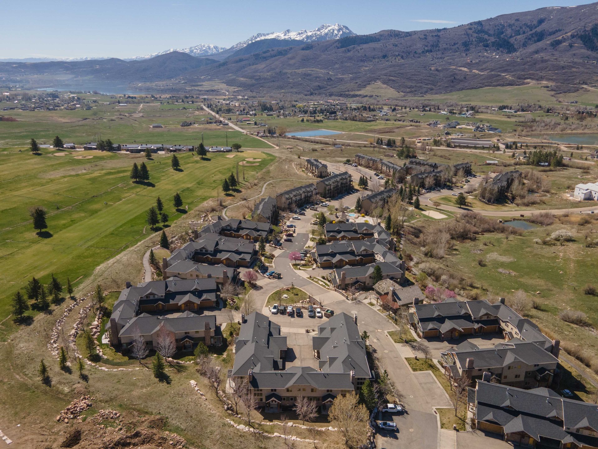 Aerial overview of property's location with a water and mountain view, nearby suburban area, and a local golf course