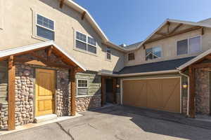 View of front of home featuring stone siding, stucco siding, a garage, roof with shingles, and asphalt driveway