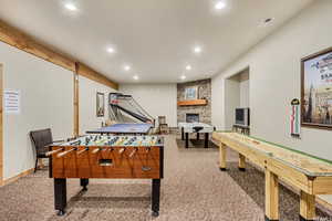 Recreation room with light colored carpet, recessed lighting, and a fireplace
