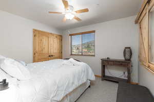 Bedroom featuring light colored carpet, a ceiling fan, and a closet