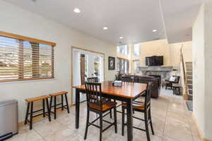 Dining area with a fireplace, recessed lighting, light tile patterned flooring, and french doors