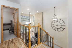 Hallway featuring an upstairs landing, light wood-style floors, and recessed lighting