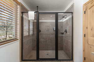 Full bath featuring a stall shower and a textured ceiling