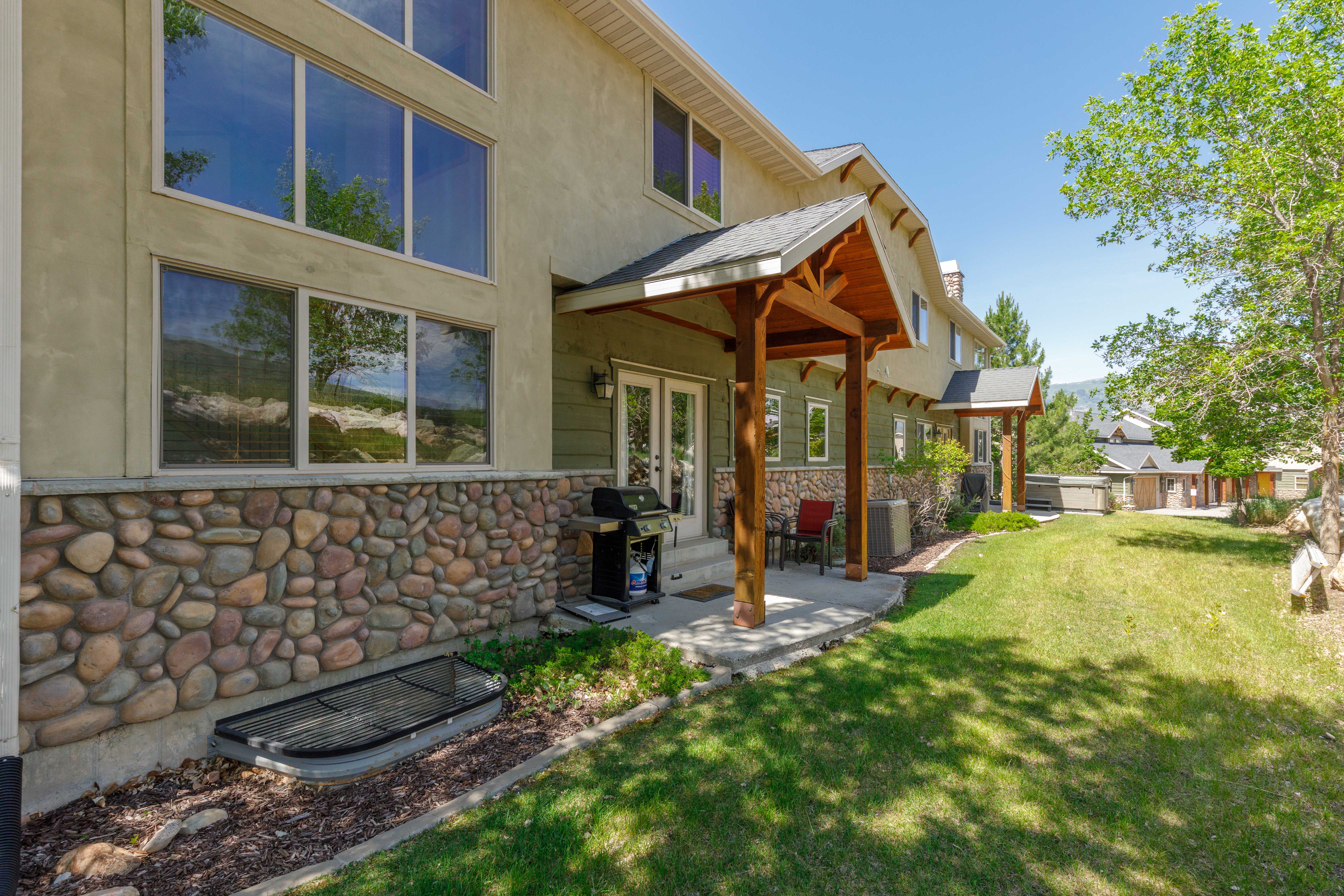 Expansive exterior featuring a natural stone foundation, stucco siding, and multiple large windows