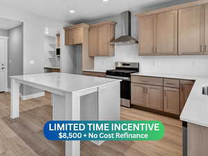 Kitchen featuring light stone countertops, stainless steel gas range, backsplash, recessed lighting, and light wood-type flooring